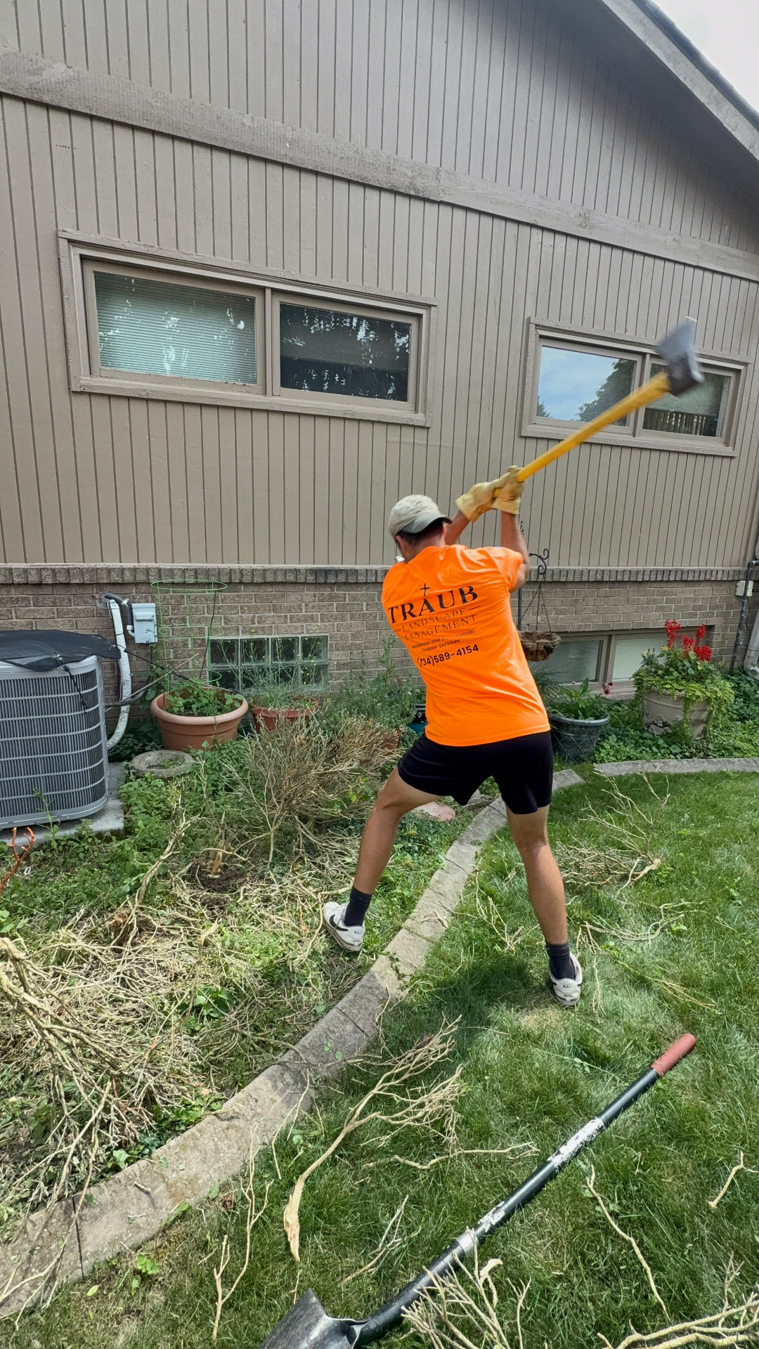 Traub team member clearing overgrowth from a residential garden bed